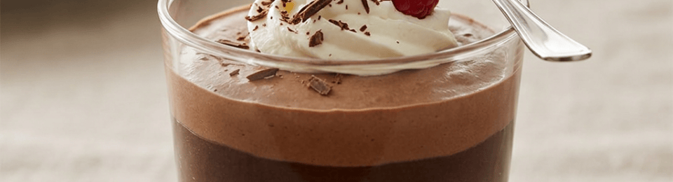 Chocolate mousse topped with whipped cream, chocolate shavings, raspberry, and mint