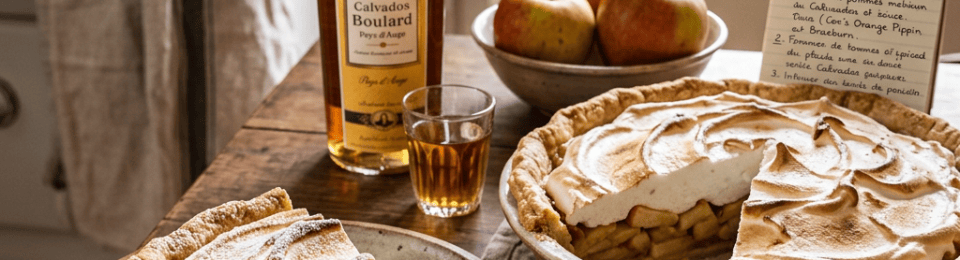 Apple meringue pie, Calvados Boulard bottle, apples, and French recipe reading “Recette : Tarte aux Pommes au Calvados & Meringuée.”